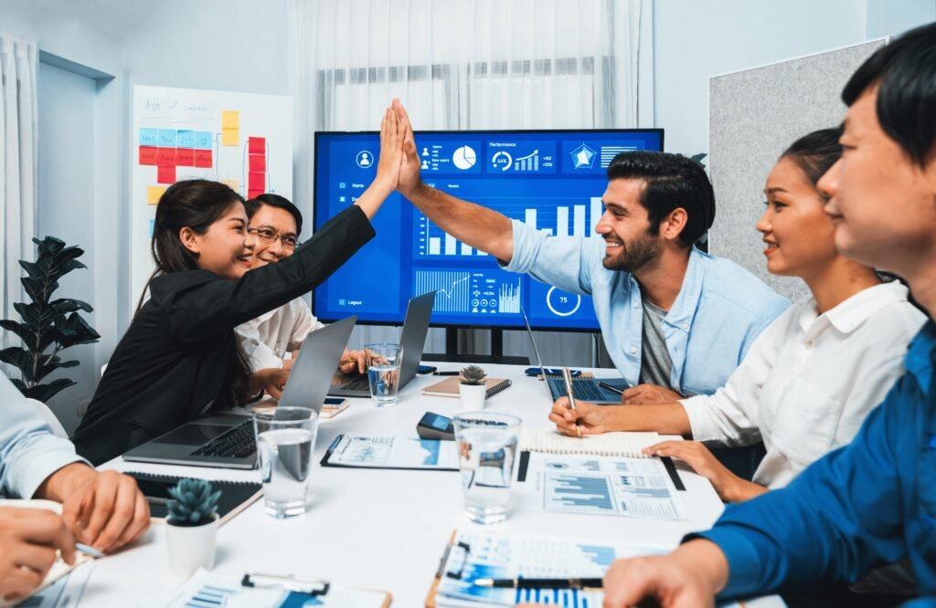 Team members celebrating a successful data analysis meeting with a high-five, using business intelligence software to drive insights and decision-making.